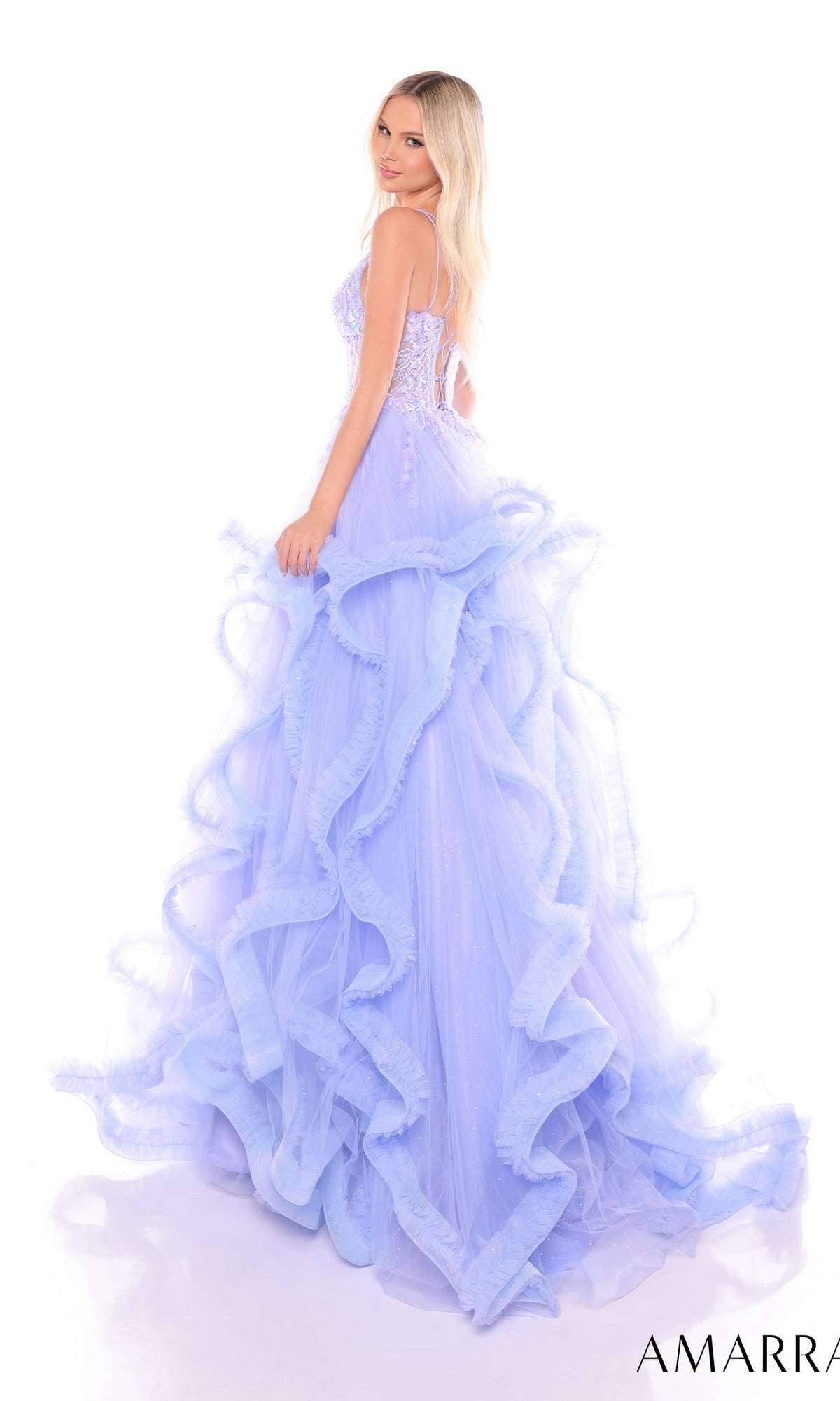 A woman poses against a white background, looking over her shoulder in the Amarra 88094 Ruffle Formal Ball Gown featuring a light purple embroidered corset bodice.